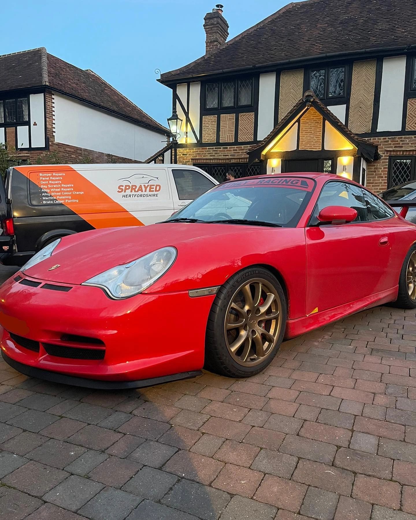 Red Porsche sports car on brick driveway